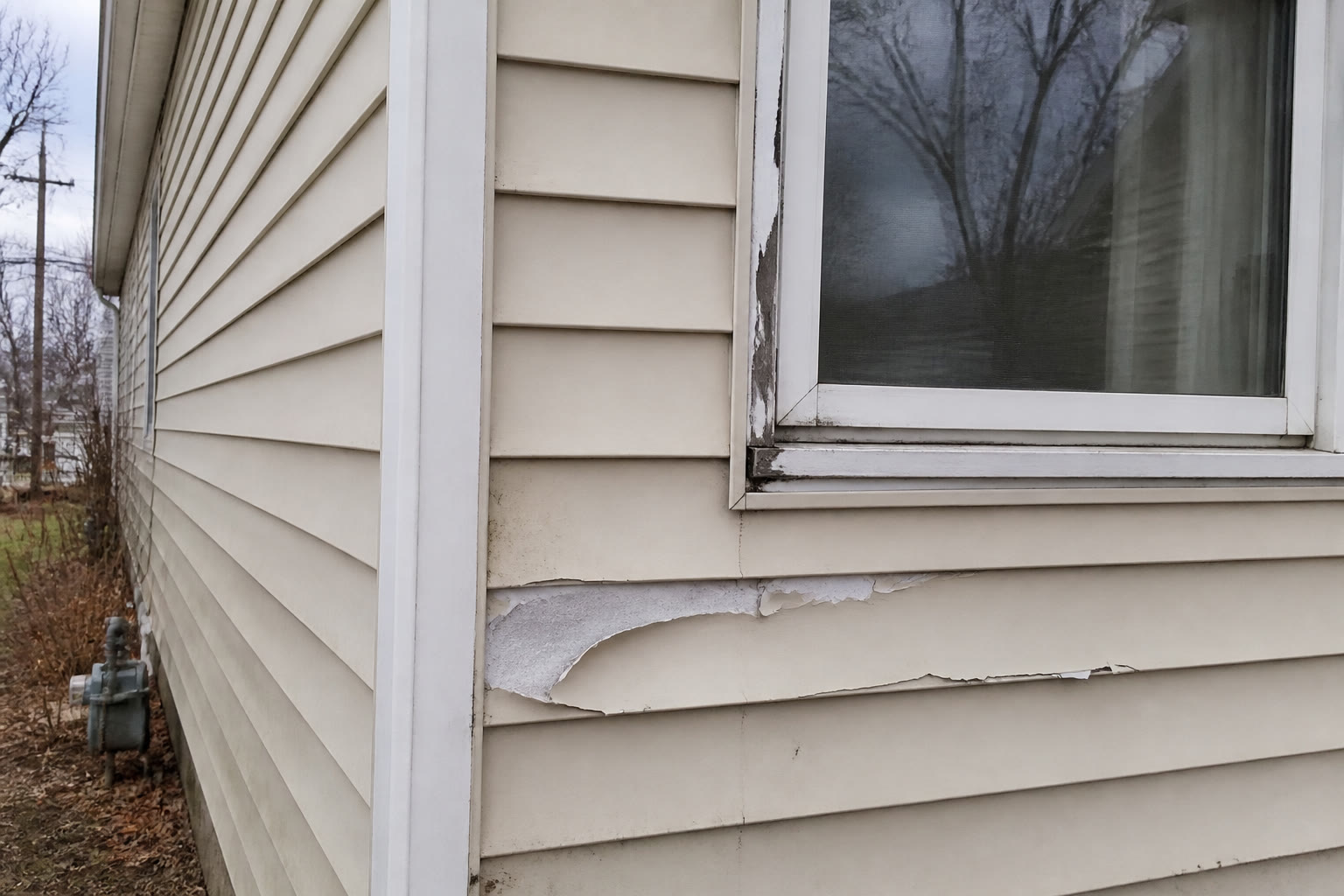Damaged peeling house siding before repair